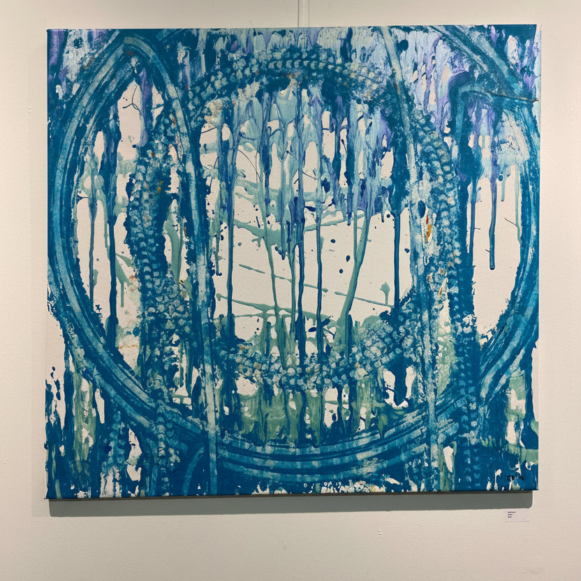 Abstract blue and white painting on a wall with a sign below.