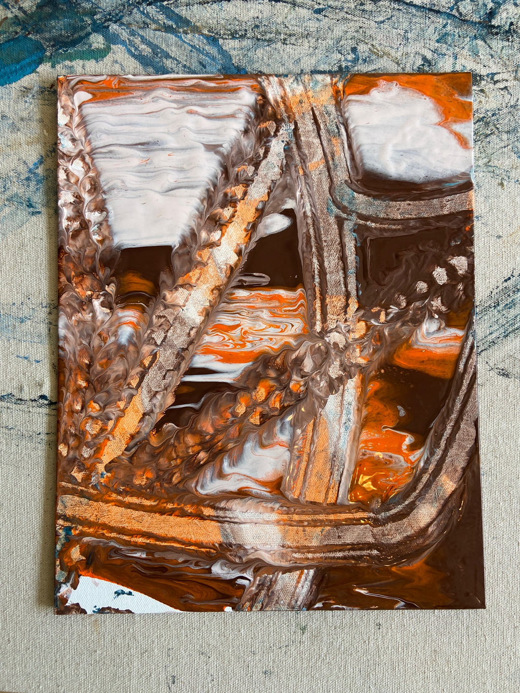 Abstract art piece with brown, orange, and white colors on a textured surface