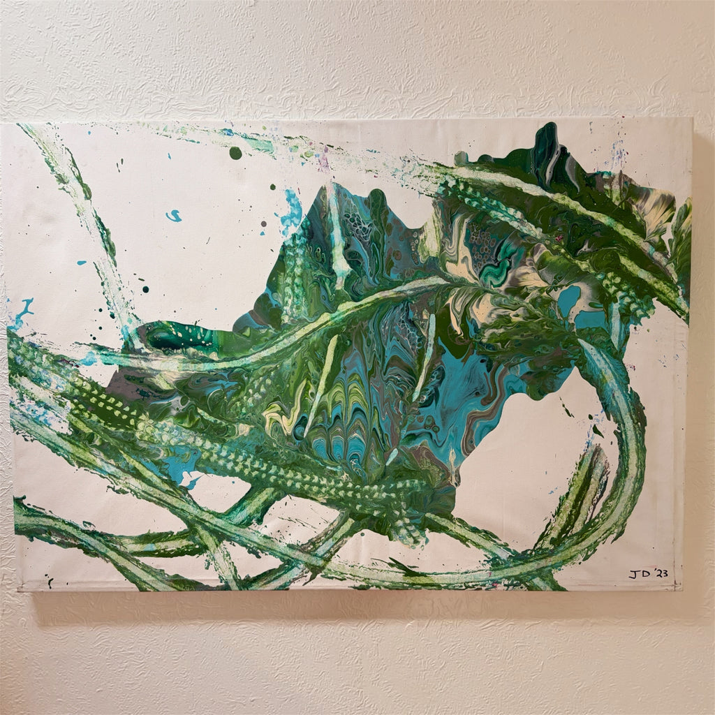An abstract fluid acrylic painting featuring swirling patterns of green, teal, and black paint on a white background, mounted on a textured beige wall.